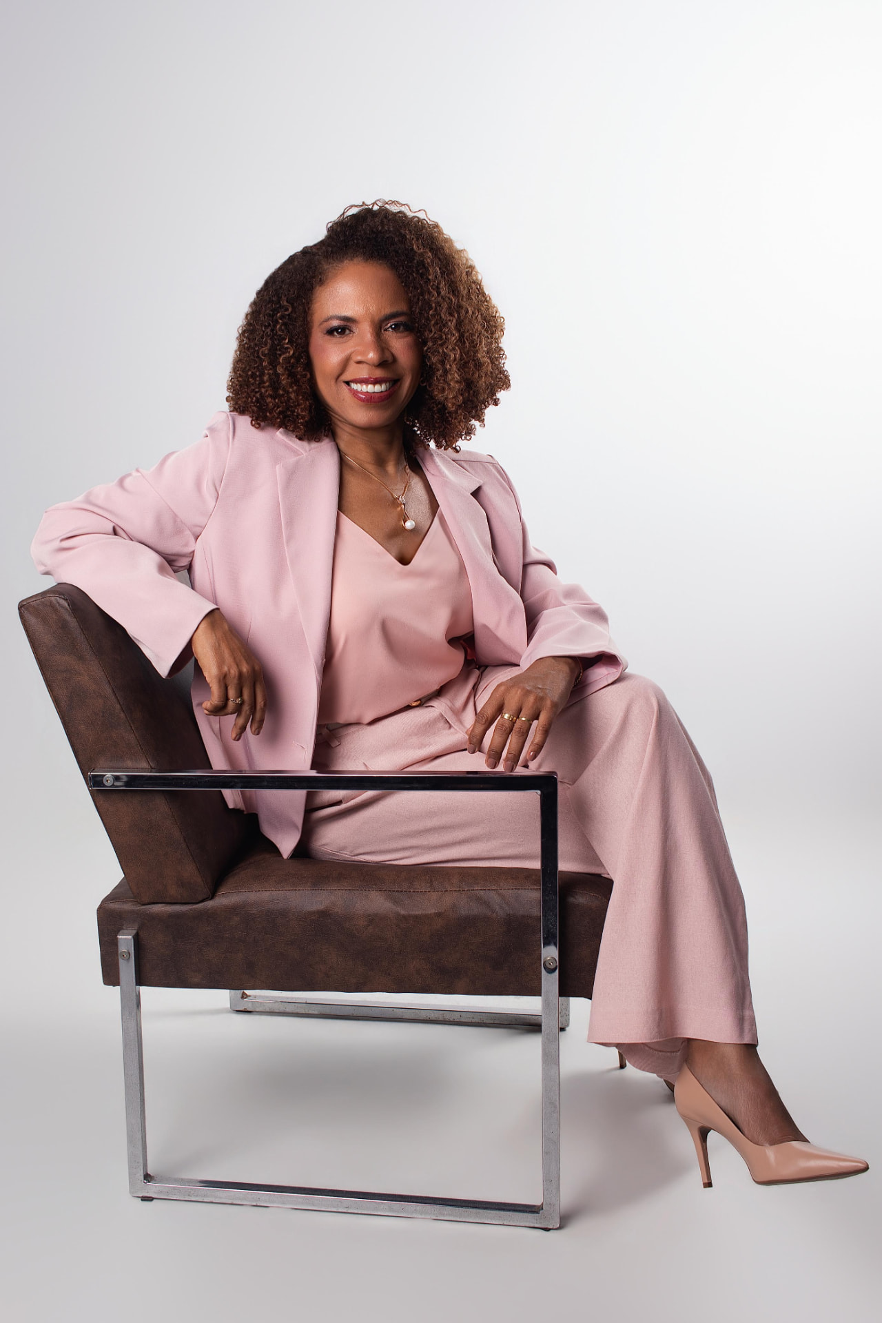 Dra. Cláudia Rodrigues sentada, com conjunto rosé